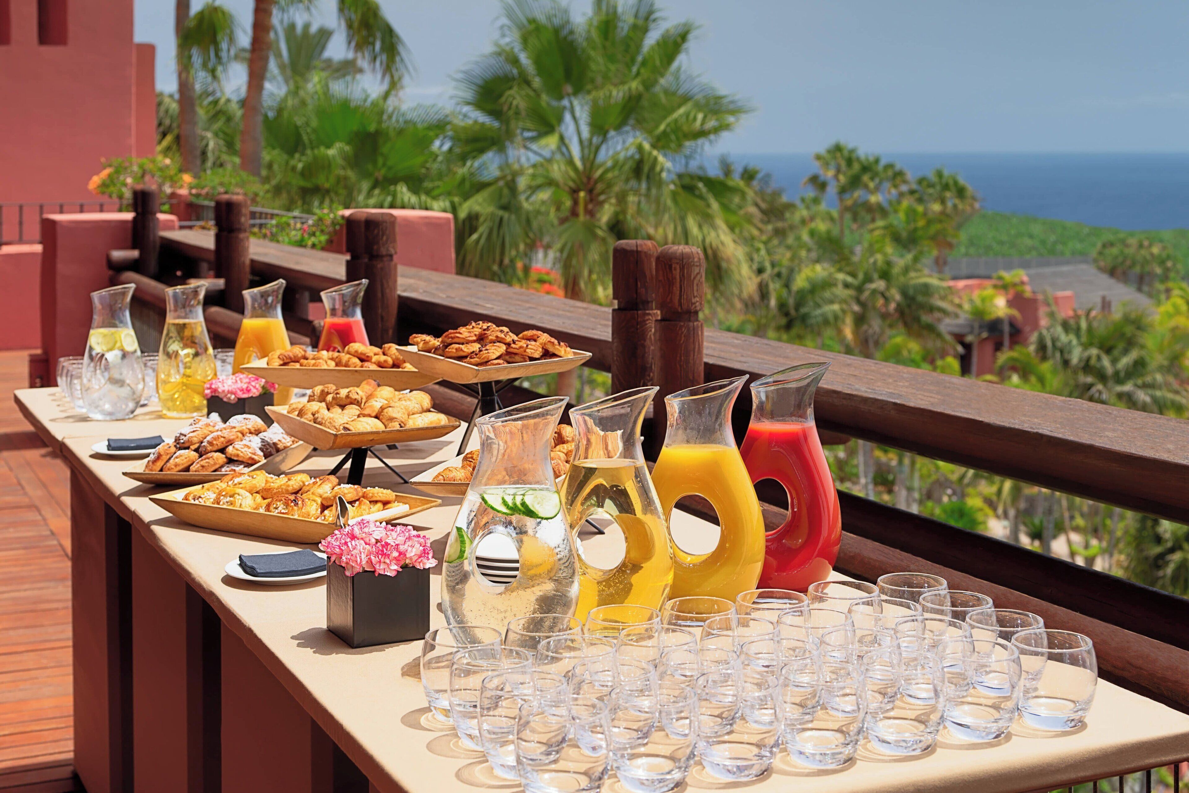 Een buffet tafel met verschillende gerechten en drankjes, met op de achtergrond een prachtig uitzicht.