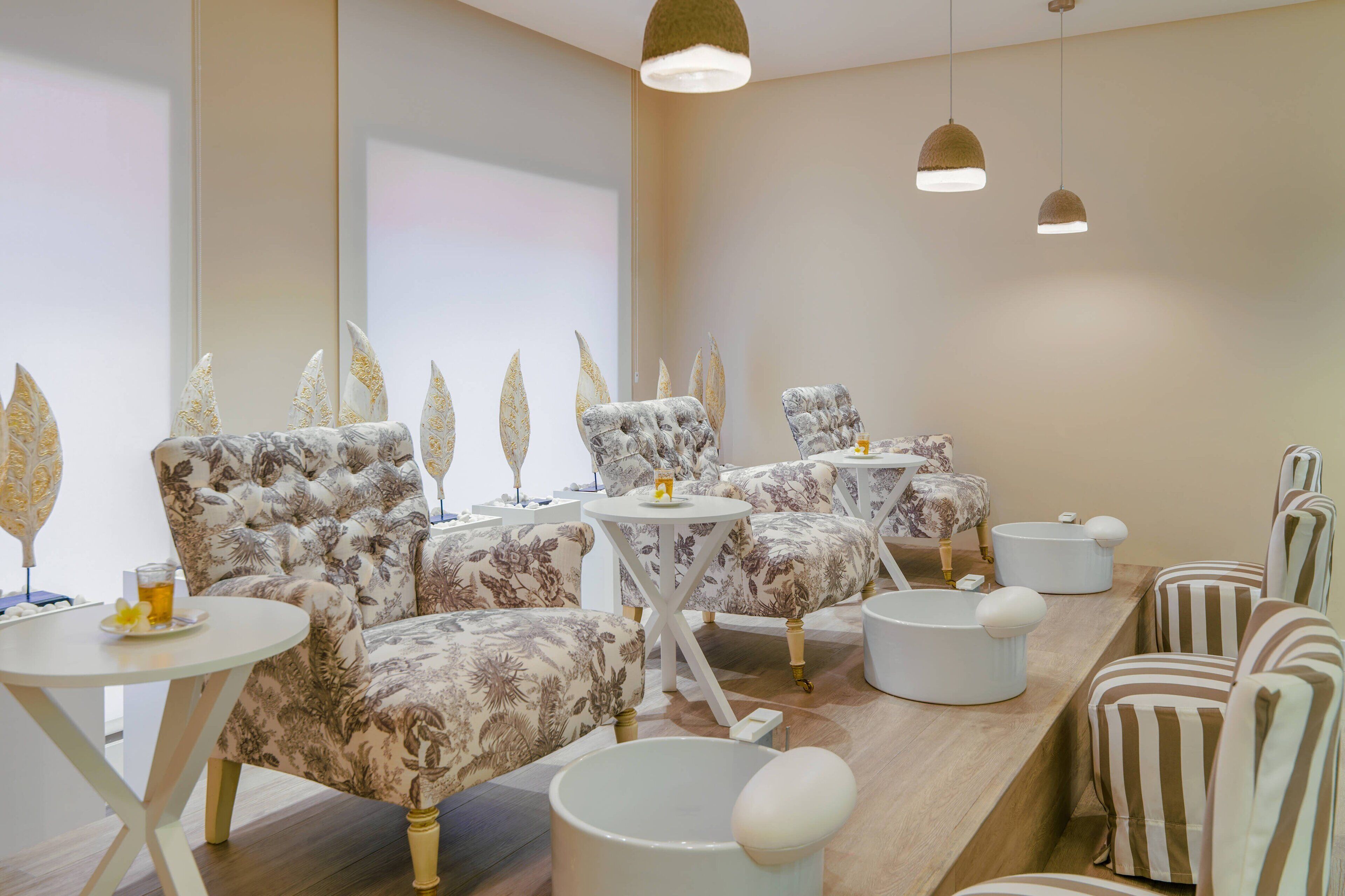 A room with floral-patterned sofas, small round tables, and a wooden reception desk.