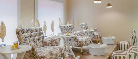 A room with floral-patterned sofas, small round tables, and a wooden reception desk.