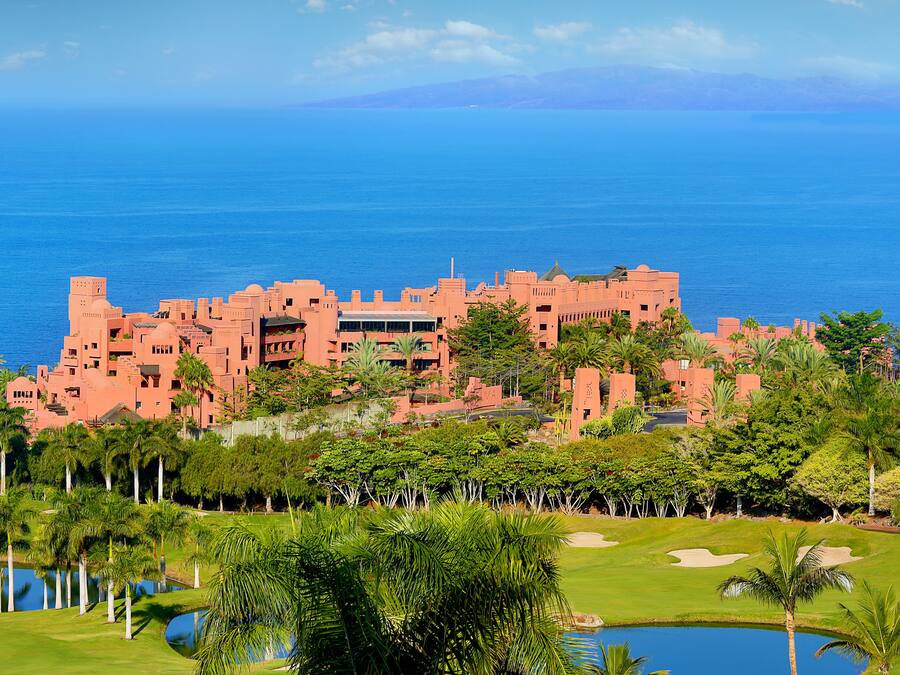 A large resort with multiple buildings, a golf course, and a body of water.