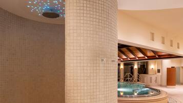 A spa area with a hot tub, tiled walls, and a ceiling with a light fixture.