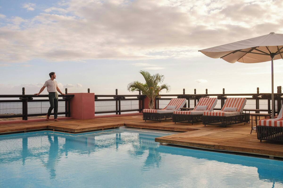 Un área de piscina con sillones de descanso y una terraza de madera.