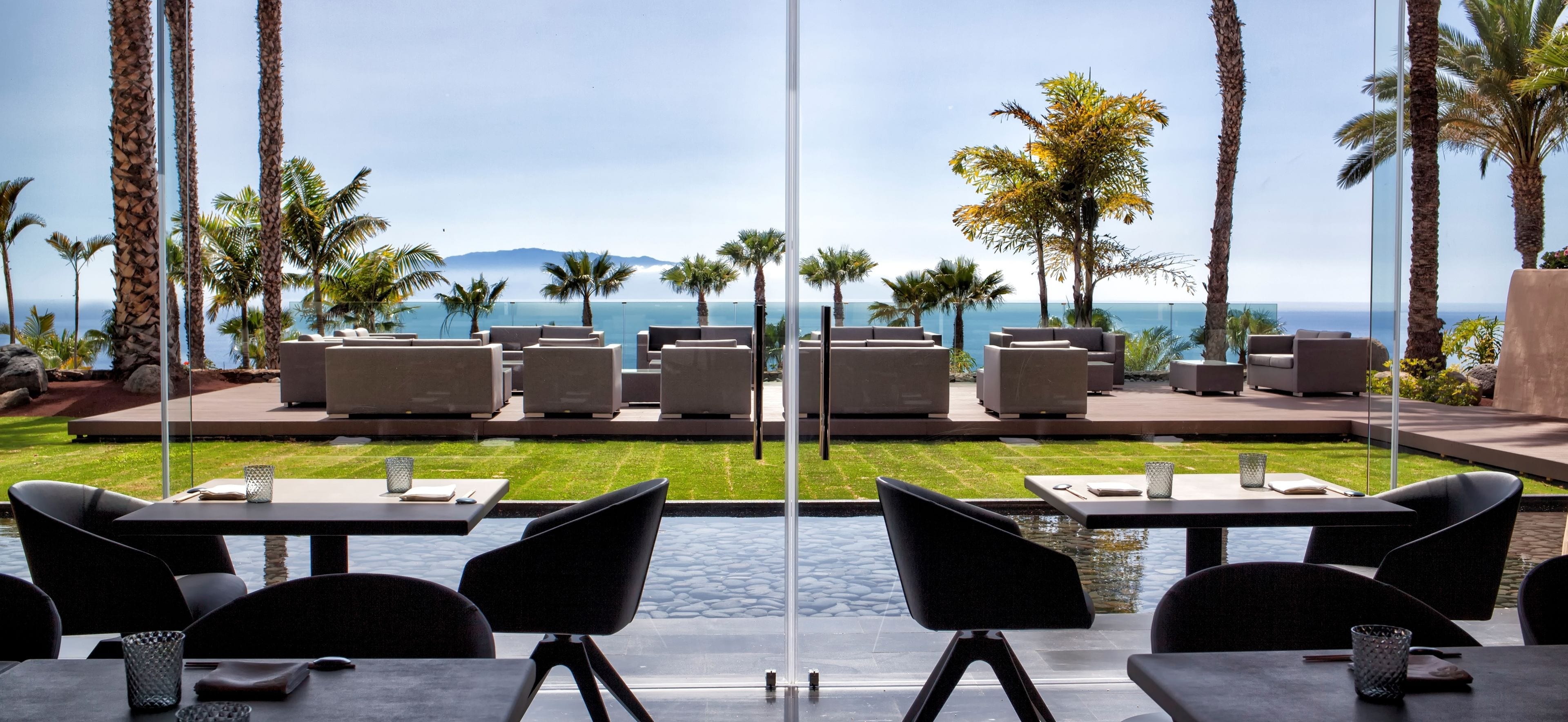 Una terraza con mobiliario exterior, piscina y vistas al océano y las montañas.