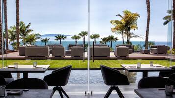 Una terraza con mobiliario exterior, piscina y vistas al océano y las montañas.