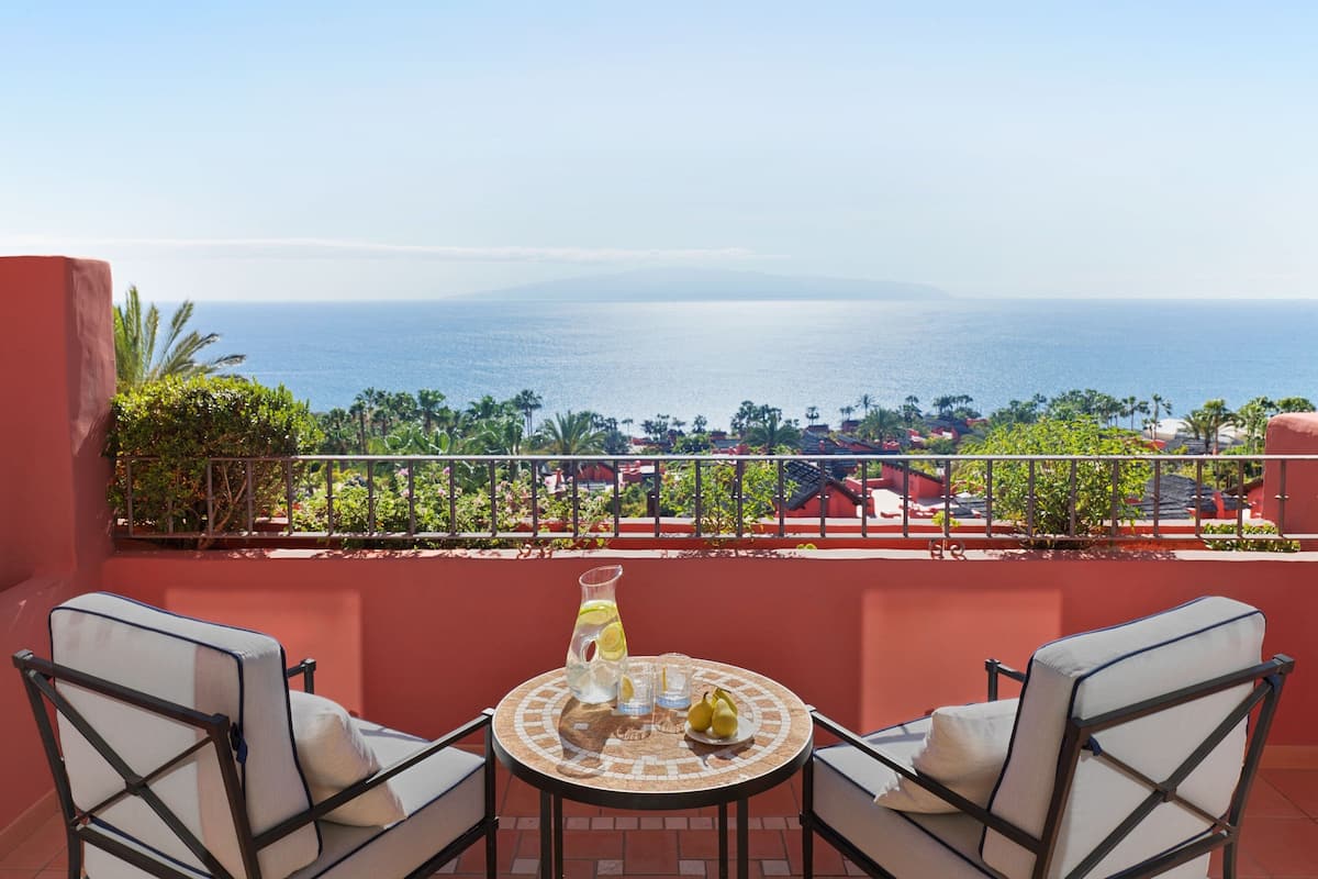 Un balcón con una mesa, dos sillas y vistas al mar.