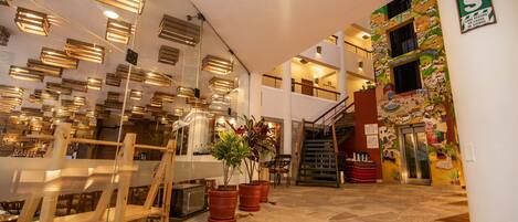 A spacious lobby with a staircase, potted plants, and a modern ceiling design.