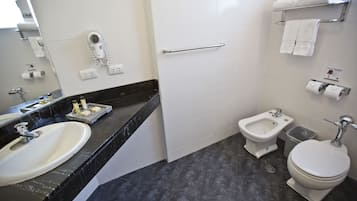 A bathroom with a sink, bidet, toilet, and a towel rack.