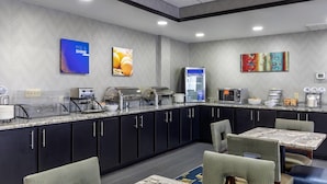 A modern kitchen with a marble countertop, black cabinets, and a seating area with patterned chairs.