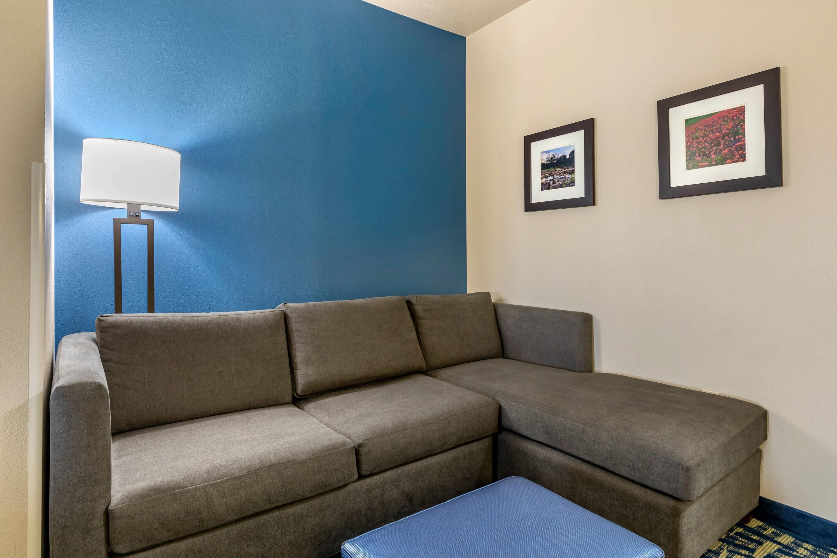 A sectional sofa, a floor lamp, and two framed pictures on the wall.