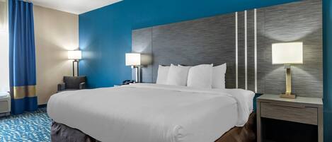 A hotel room with a large bed, two bedside lamps, a nightstand, and a patterned carpet.