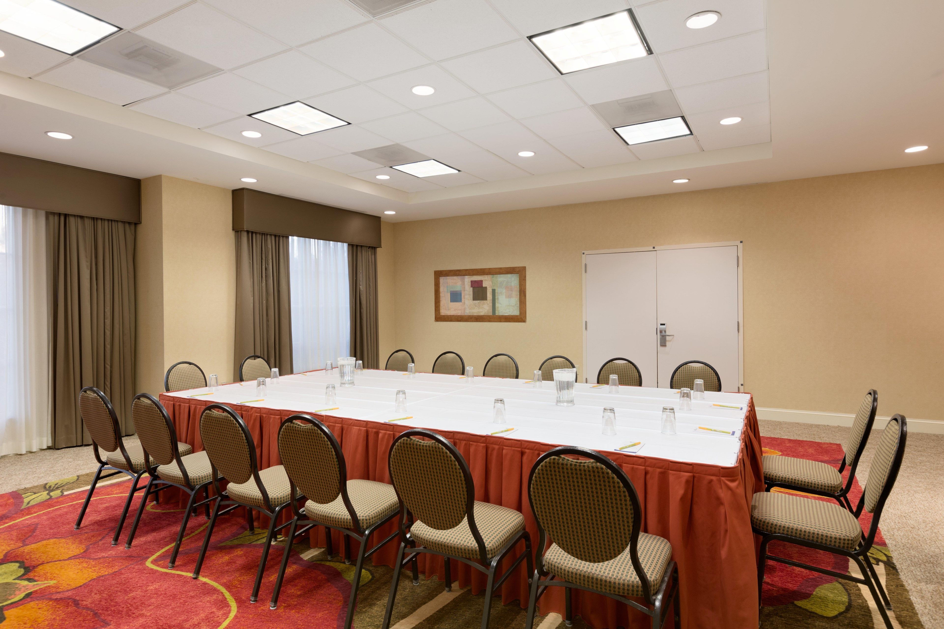 A conference room with a long table, chairs, a whiteboard, and a carpeted floor.
