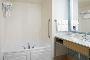 Een moderne badkamer met een badkuip, een wastafel, een spiegel en een handdoekrek.