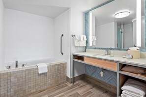 A modern bathroom with a bathtub, a vanity with a mirror, and a towel rack. - Hilton Garden Inn Fredericksburg (Fredericksburg)