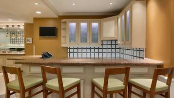 Una cocina con encimera de granito, sillas de madera y salpicadero de azulejos.