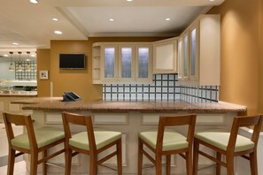 A kitchen with a granite countertop, wooden chairs, and a tiled backsplash. - Hilton Garden Inn Fredericksburg (Fredericksburg)