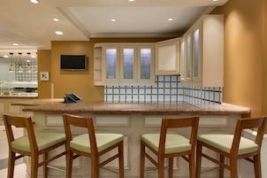 Una cocina con encimera de granito, sillas de madera y salpicadero de azulejos.