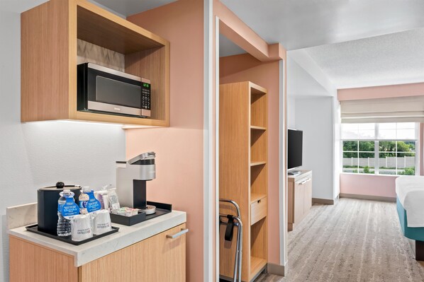 Habitación de hotel con kitchenette, microondas, cafetera y ventana con vistas a zonas verdes.
