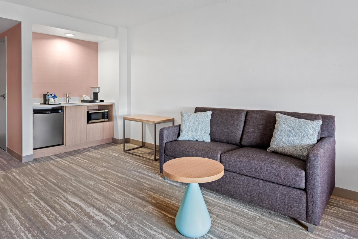A modern living room with a sofa, a coffee table, and a kitchenette area.