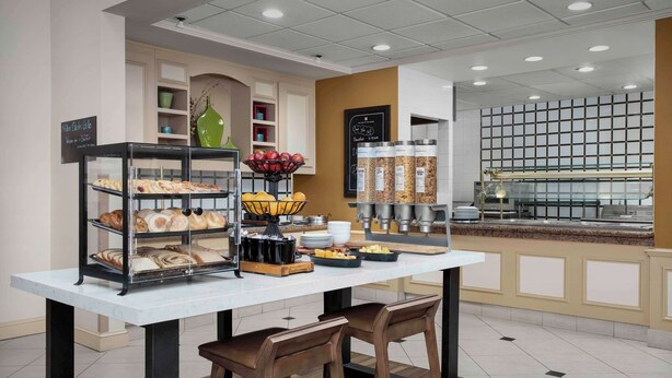 Un bar où l’on prend le petit-déjeuner, avec un présentoir de pâtisseries, un panier de fruits et le matériel nécessaire pour préparer le café.