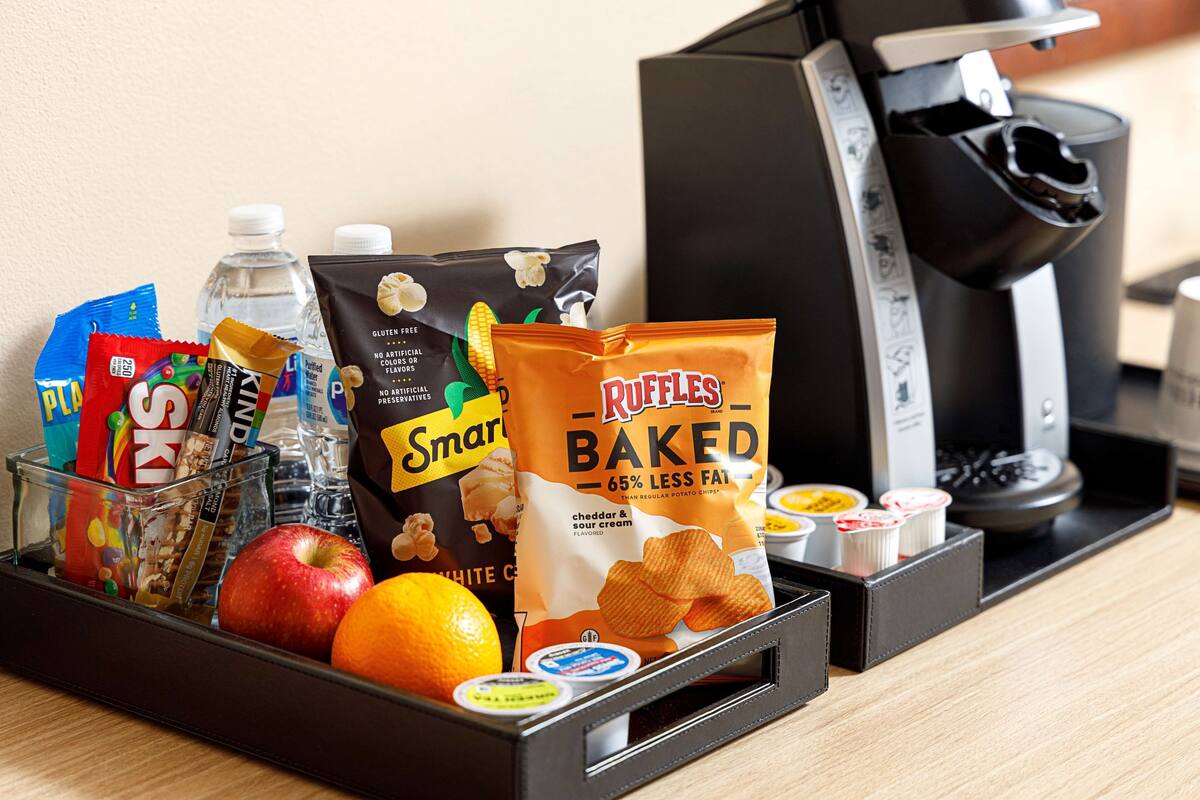 A tray with snacks, a bottle of water, an apple, and a bag of baked chips.