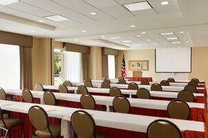 Un salón de conferencias con varias mesas y sillas, una pantalla de proyector y una bandera estadounidense.