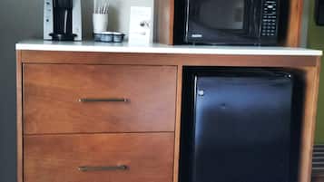 A compact kitchenette with a coffee maker, microwave, and a small refrigerator.