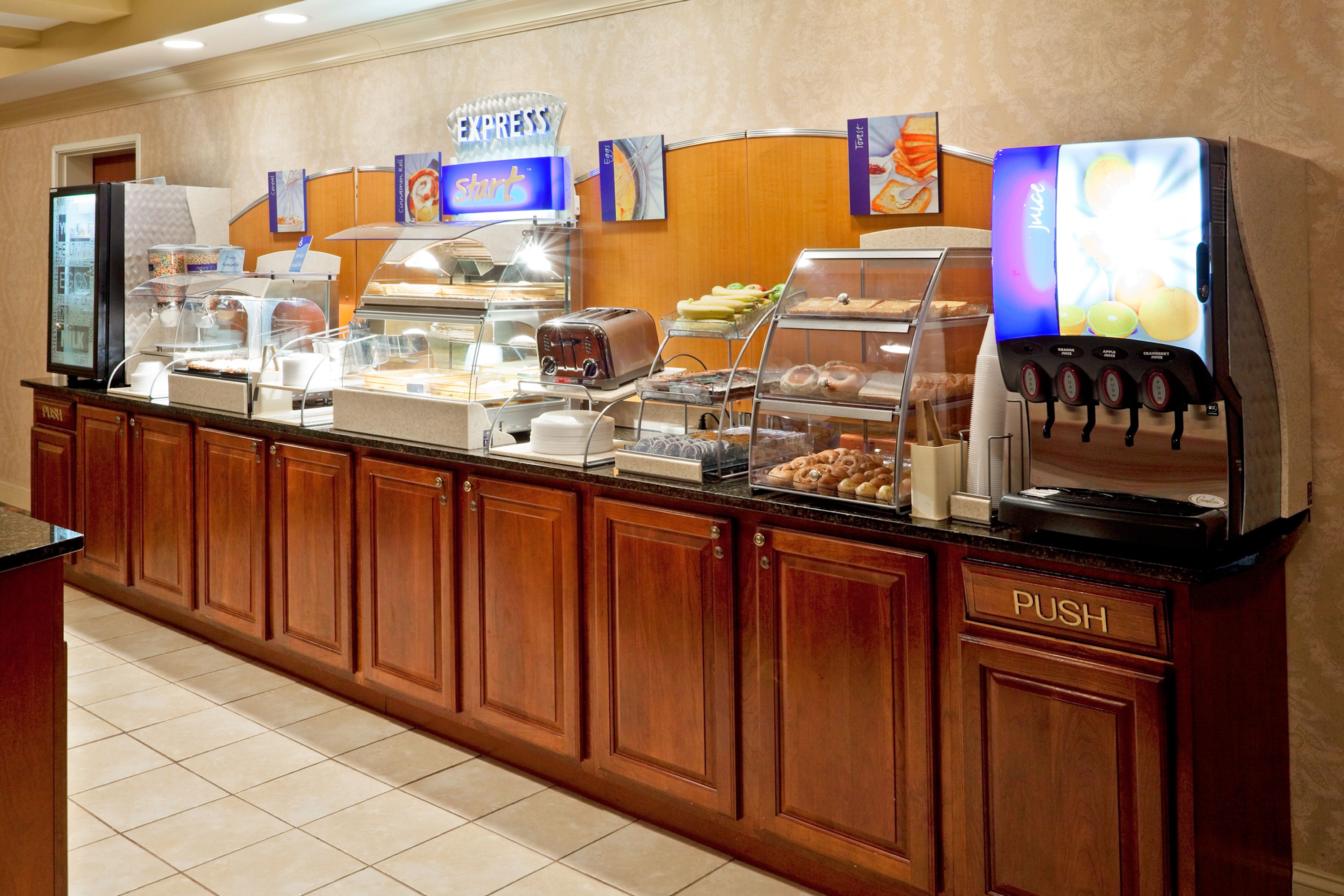 A buffet counter with a juice dispenser, a toaster, and various food items.