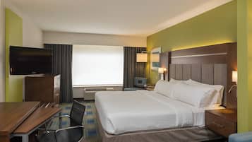 Una habitación de hotel con cama, escritorio, televisor, silla y ventana.