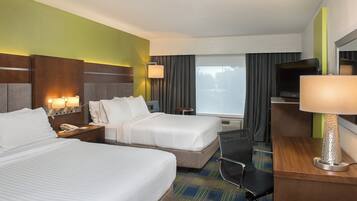 A hotel room with two beds, a desk, a chair, a TV, and a window with curtains.