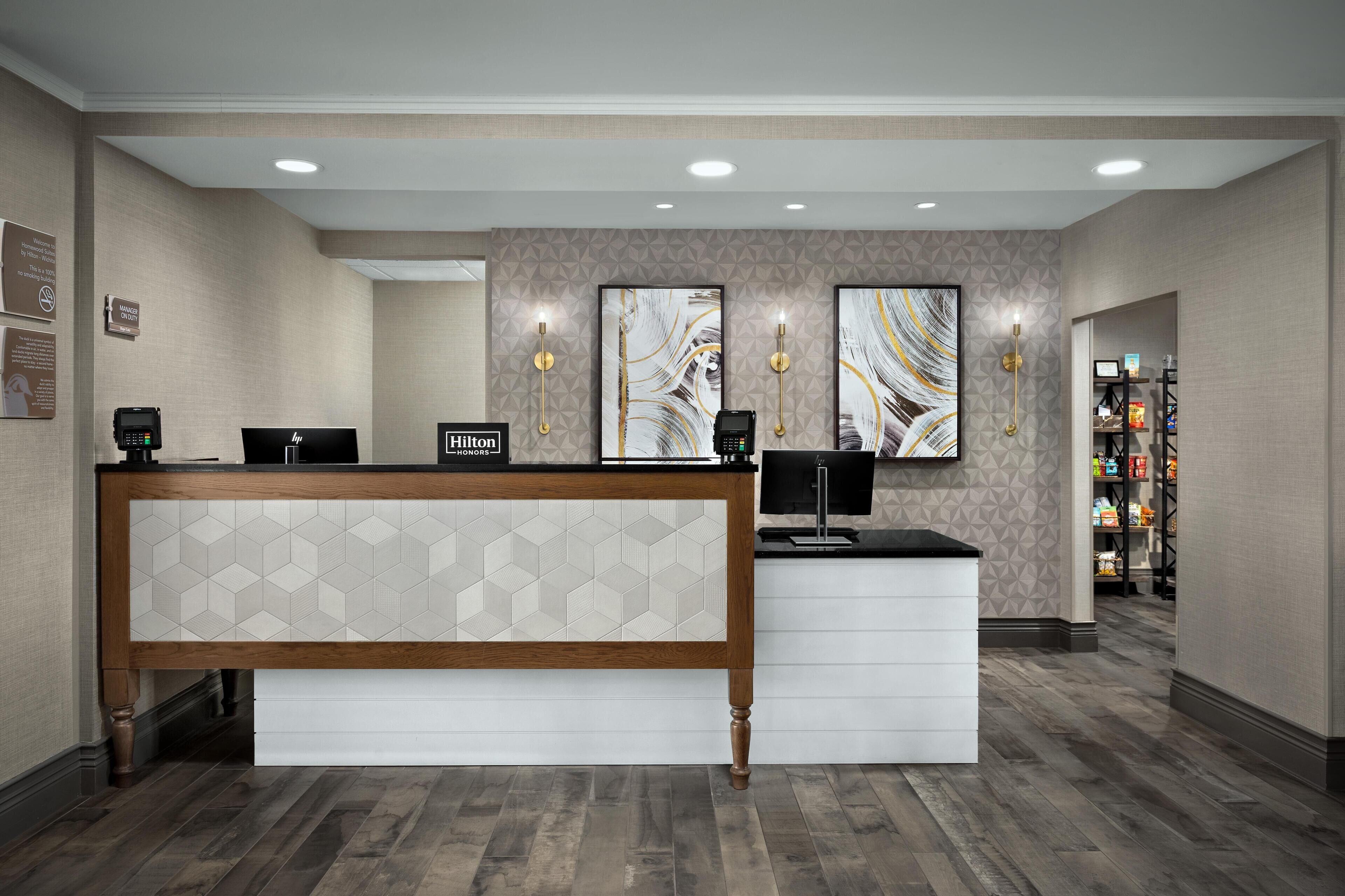 Een hotel receptie met een modern ontwerp, een digitaal incheckstation en een kunstwerk aan de muur.