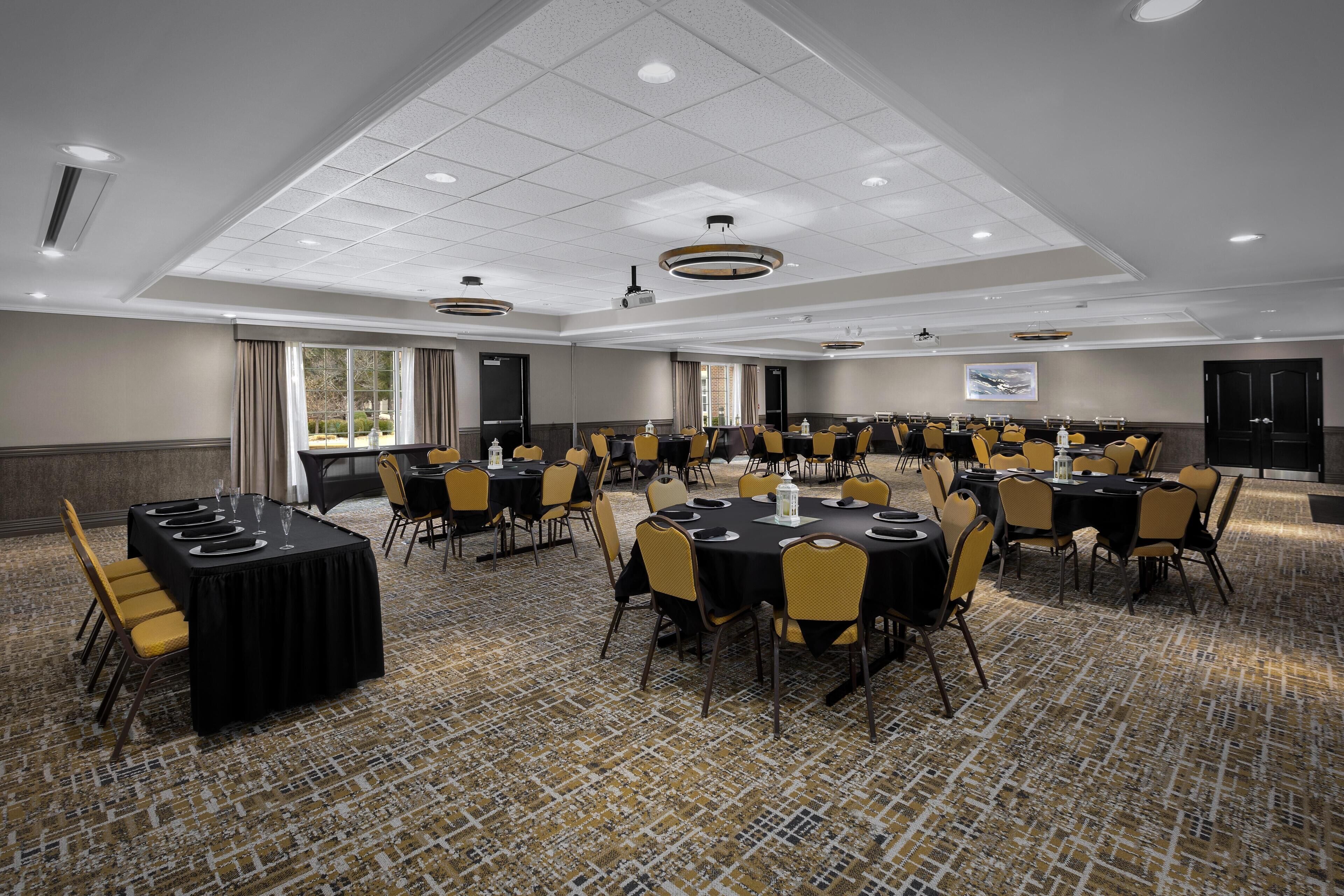 A conference room with multiple tables and chairs, a projector, and a large window.