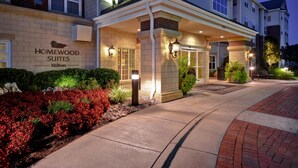 Entrada de un hotel con un letrero de 'Homewood Suites Hilton' y un corredor cubierto.