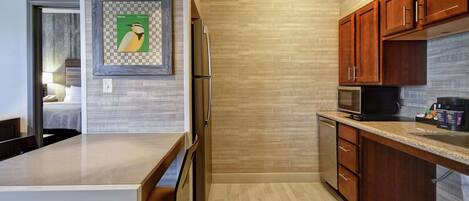 A modern kitchen with wooden cabinets, a stainless steel refrigerator, and a granite countertop.