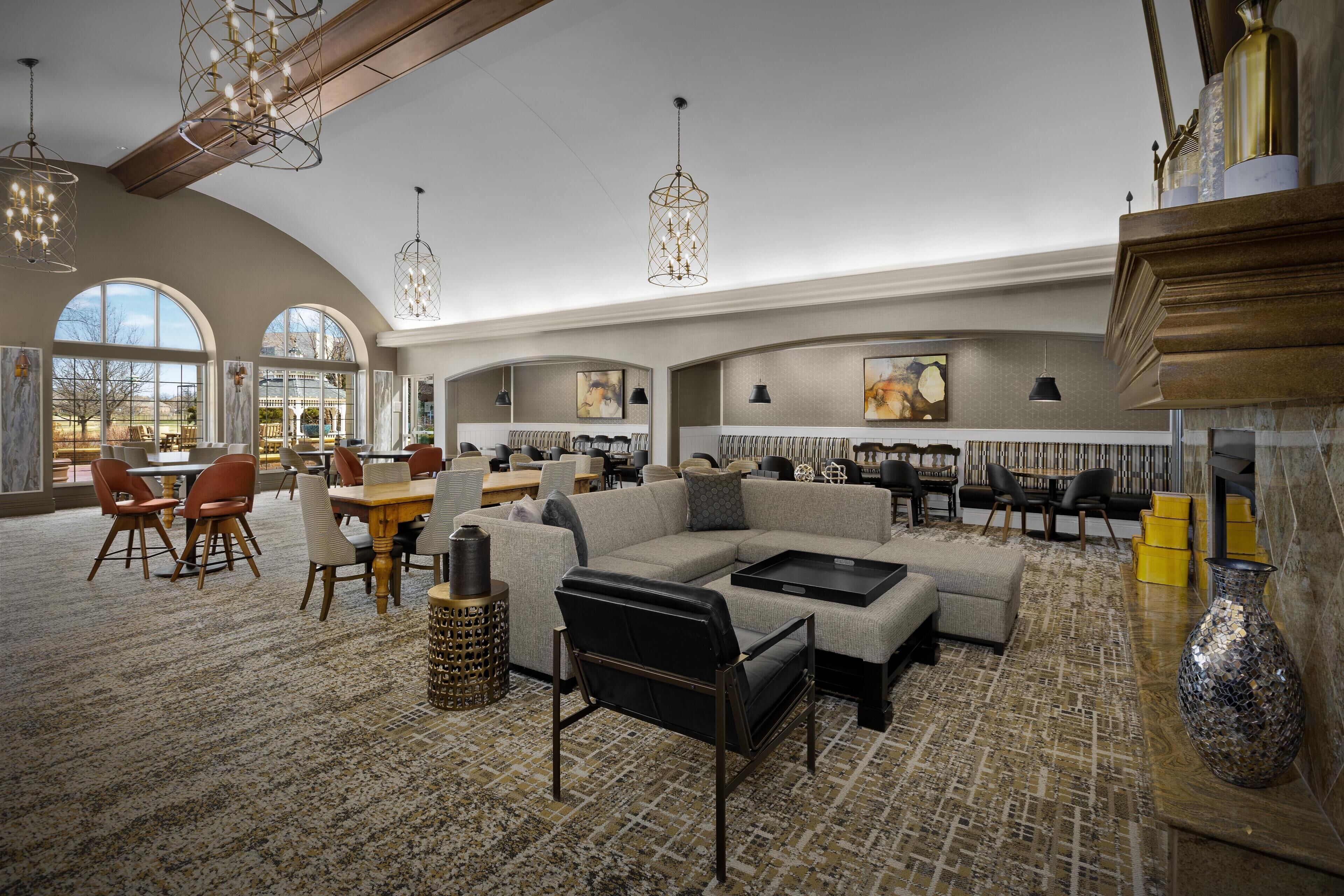 A spacious lounge area with a sectional sofa, dining tables, and chairs.