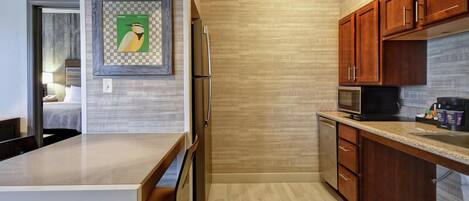 A modern kitchen with wooden cabinets, a stainless steel refrigerator, a microwave, and a dining area with a table and chairs.