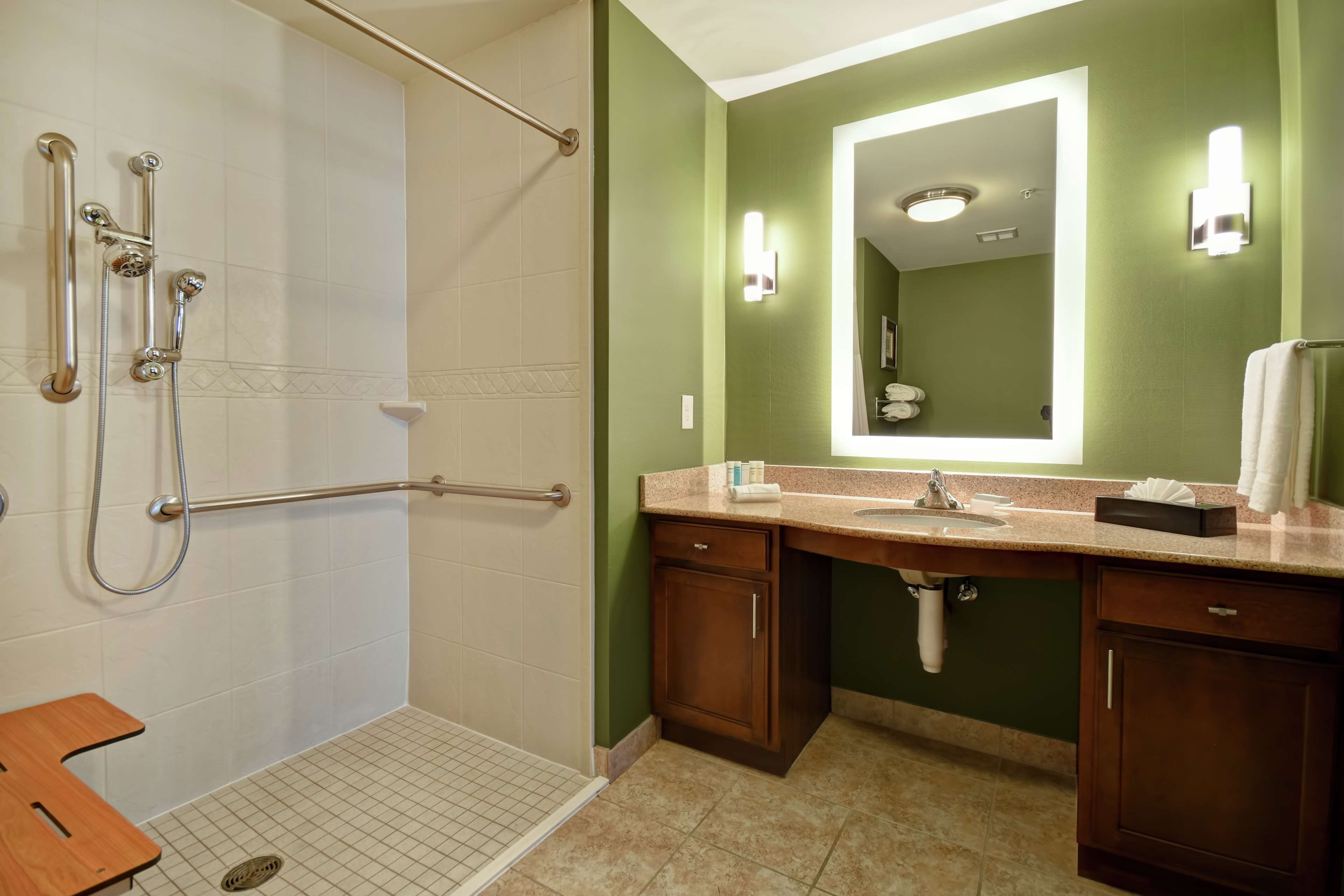 A bathroom with a walk-in shower, a sink, and a mirror.