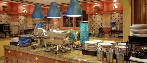 A buffet area with multiple serving stations, including a waffle station, and a variety of utensils and dishes neatly arranged on the counter.