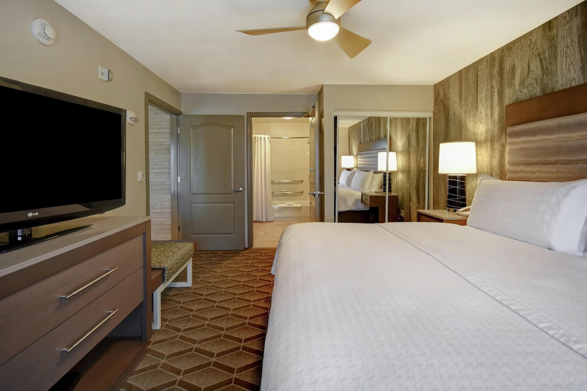 Ein Hotelzimmer mit Bett, Fernseher, Kleiderschrank und Duschbereich.