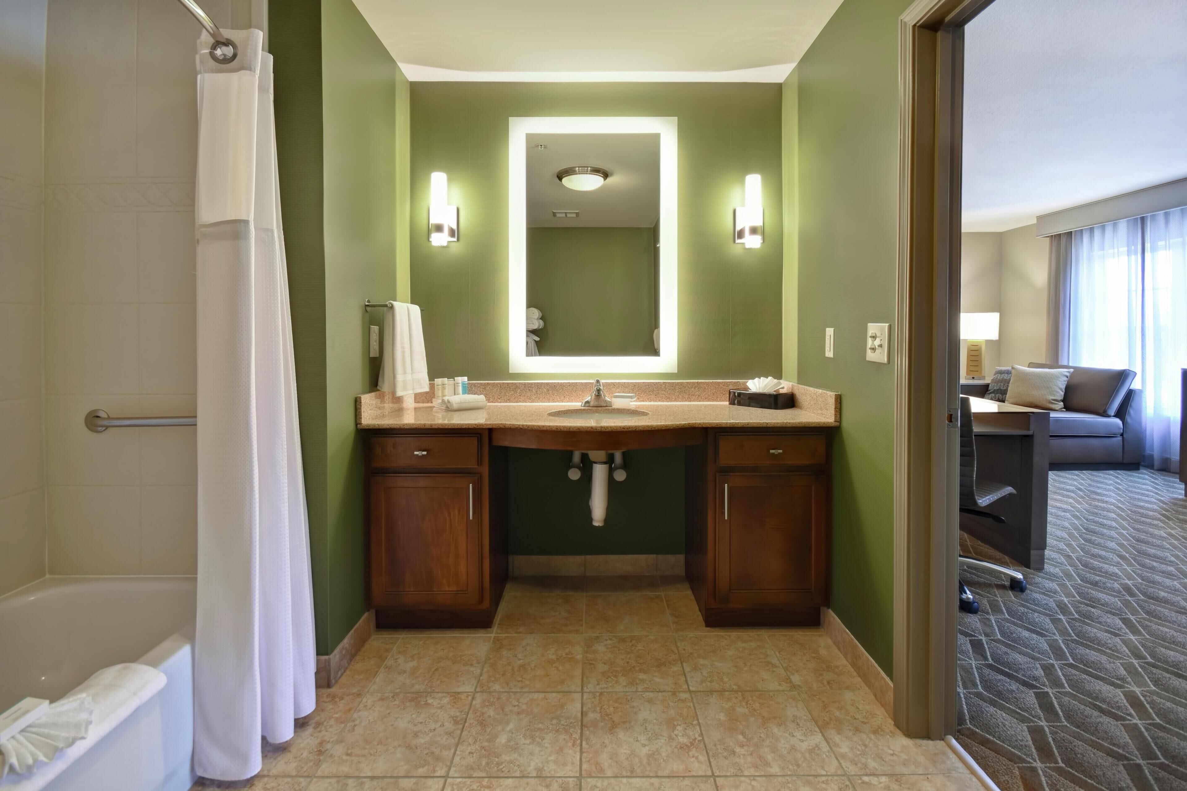 A hotel bathroom with a shower, a sink, and a mirror.