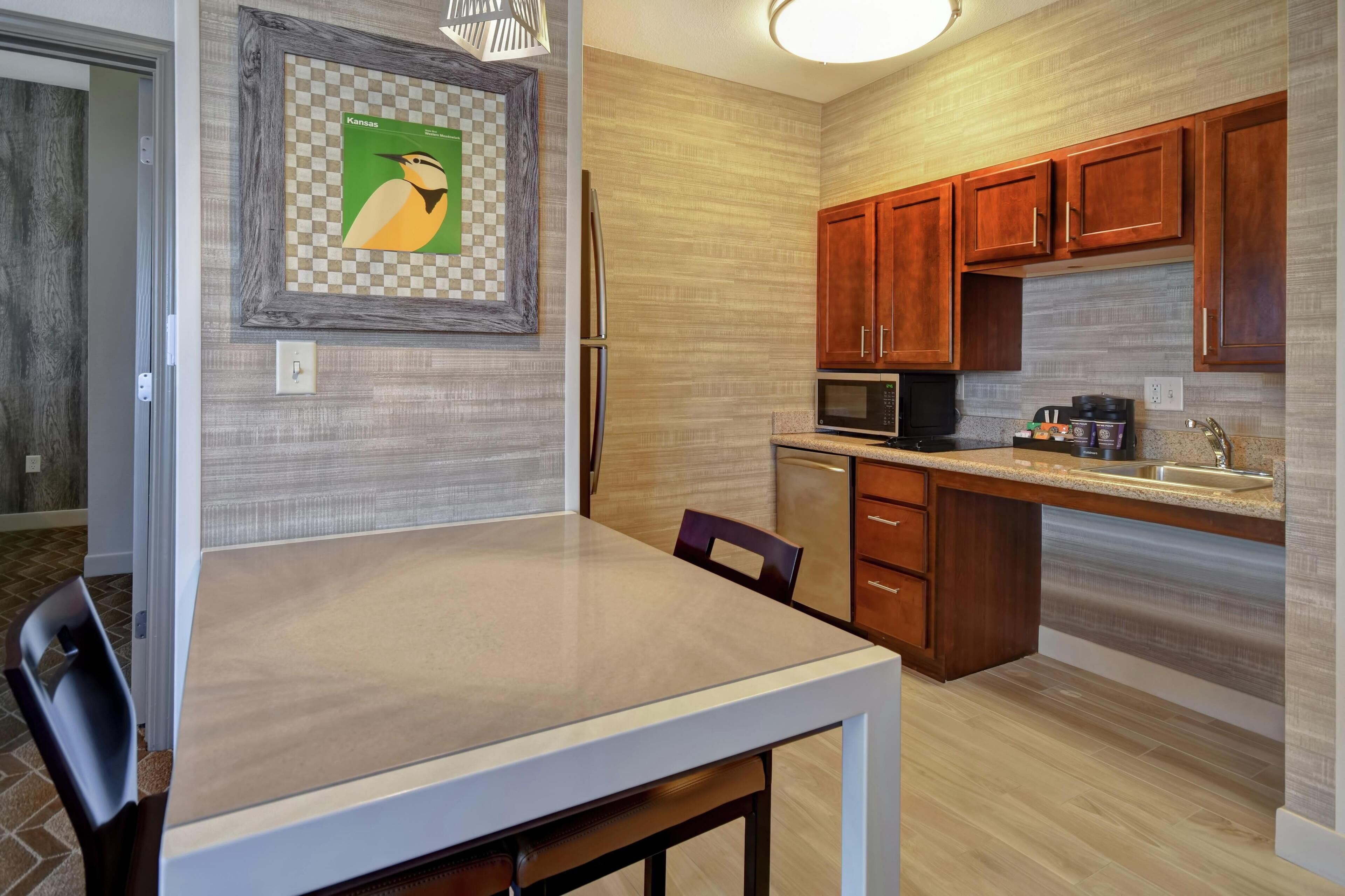 Una cocina moderna con armarios de madera, refrigerador, microondas y una mesa de comedor con sillas.