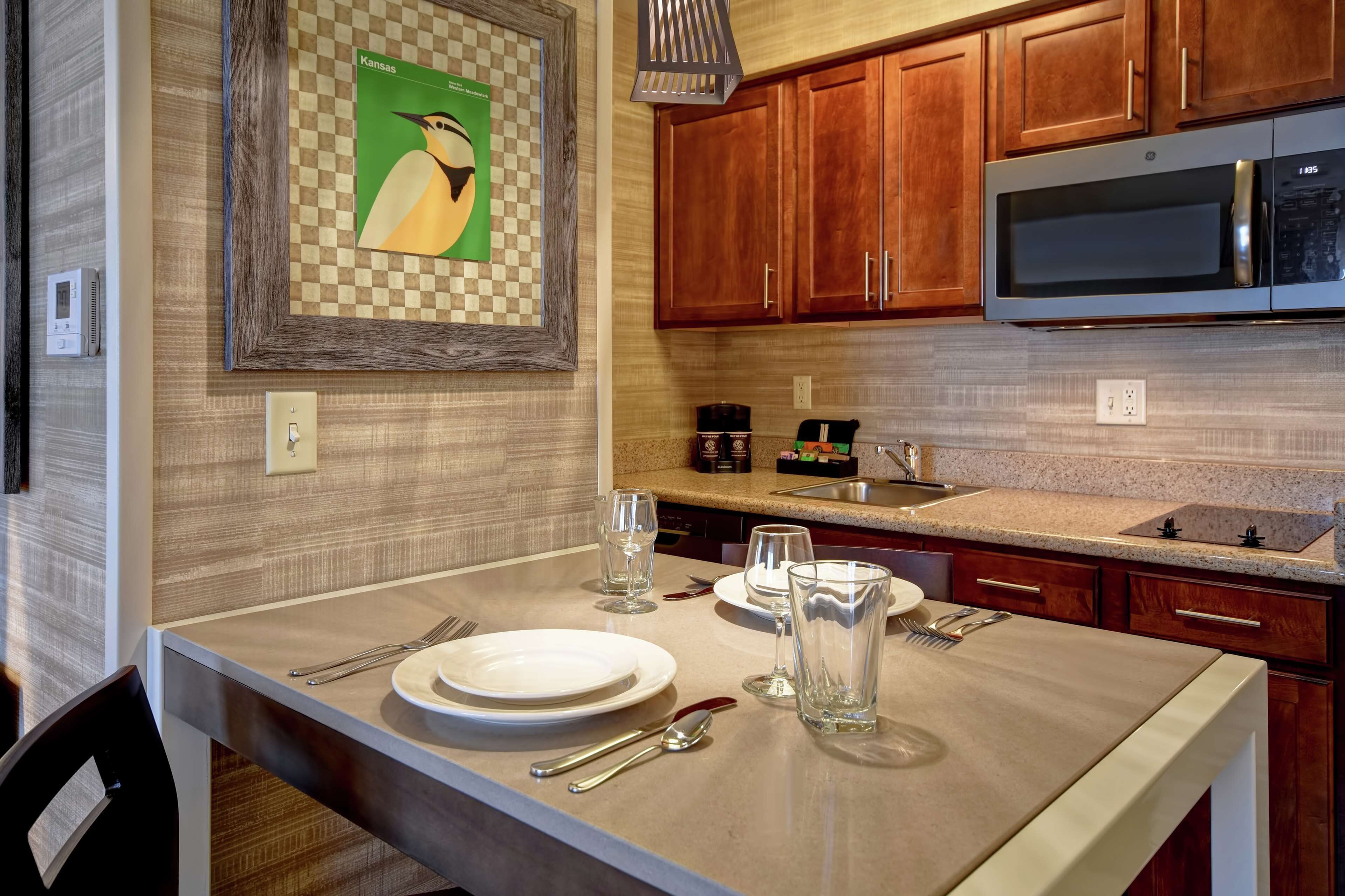 A modern kitchen with wooden cabinets, a stainless steel microwave, and a checkered wall art piece.