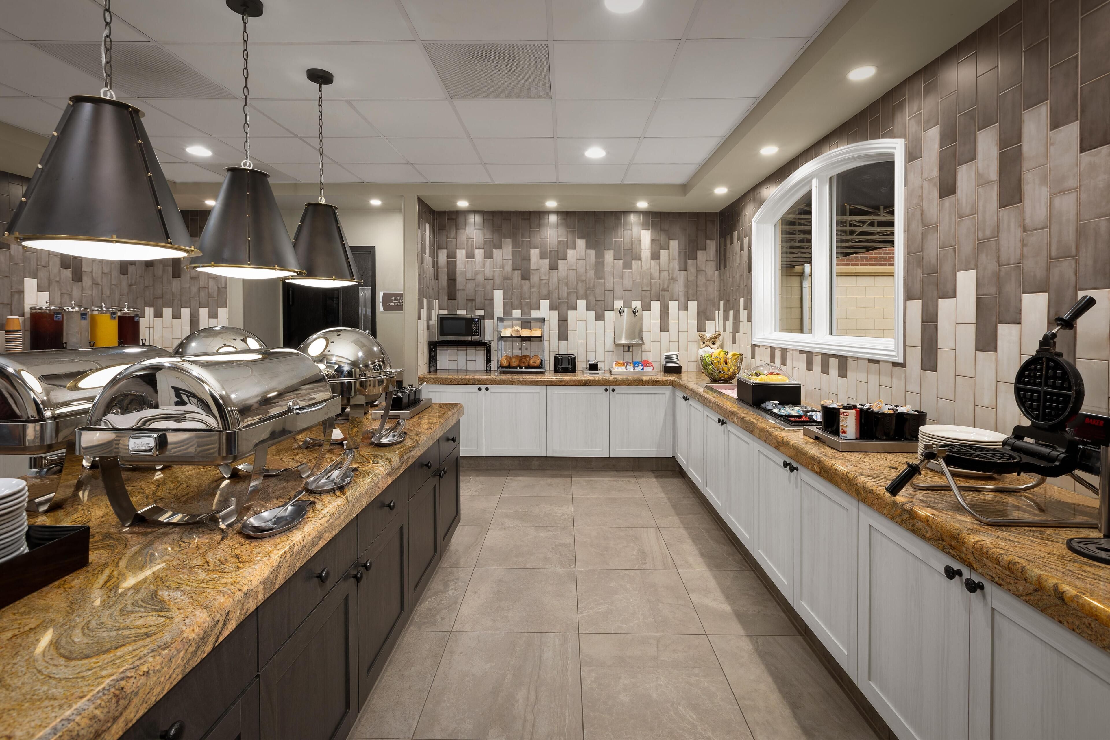 A modern kitchen with granite countertops, stainless steel appliances, and pendant lighting.