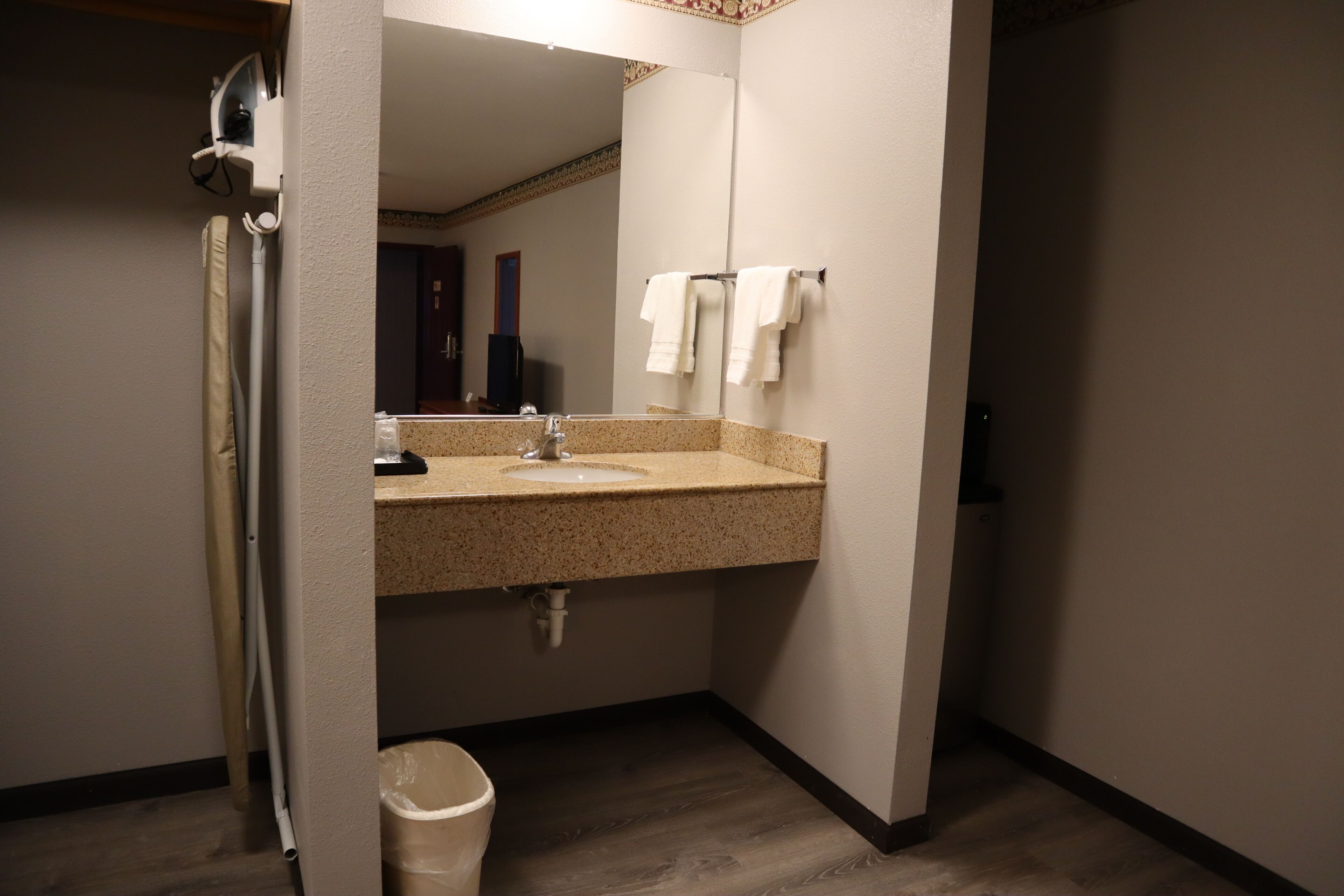 A bathroom with a sink, mirror, and towel rack.