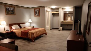Habitación de hotel con cama, mesitas de noche, escritorio, espejo y baño con ducha y lavamanos.