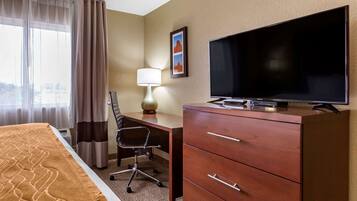 A hotel room with a bed, a desk with a chair, a television, and a dresser.