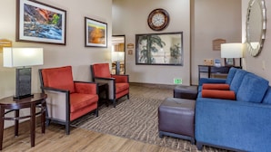 A hotel lobby with red and blue seating, framed pictures on the walls, a clock, and a mirror.