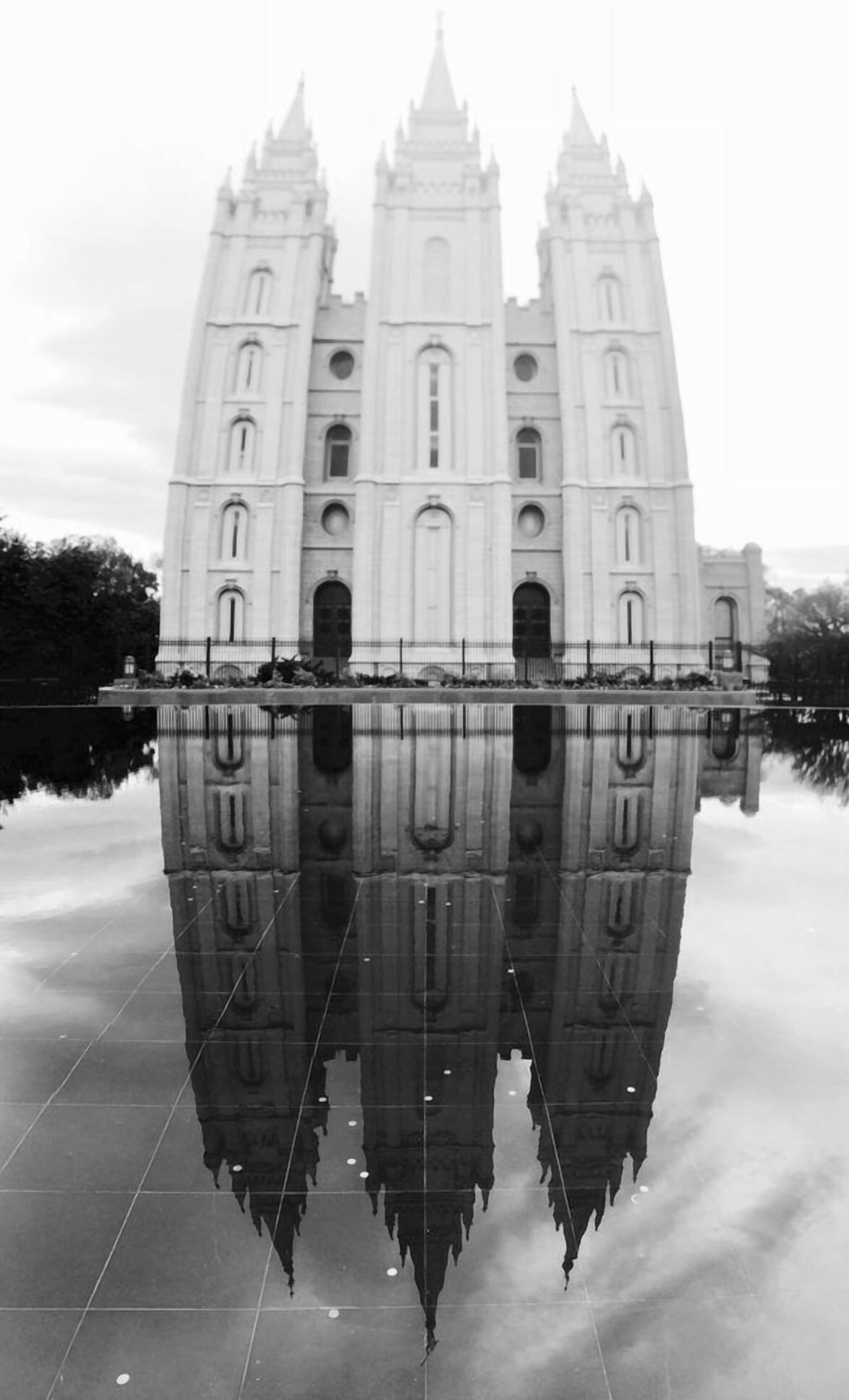 Una catedral gótica grande y blanca, con tres torres, reflejada en aguas tranquilas.