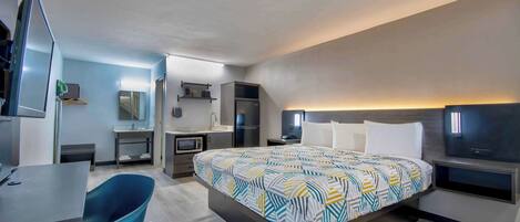 Una habitación de hotel moderna con una cama grande, un escritorio, una silla, un televisor y un baño.
