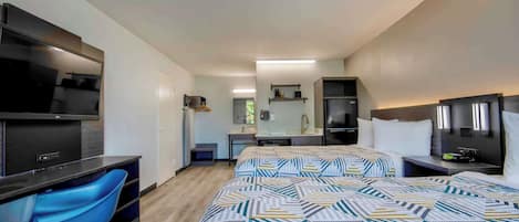 Habitación de hotel moderna con una cama grande, un escritorio con silla, televisión y un baño a la vista al fondo.