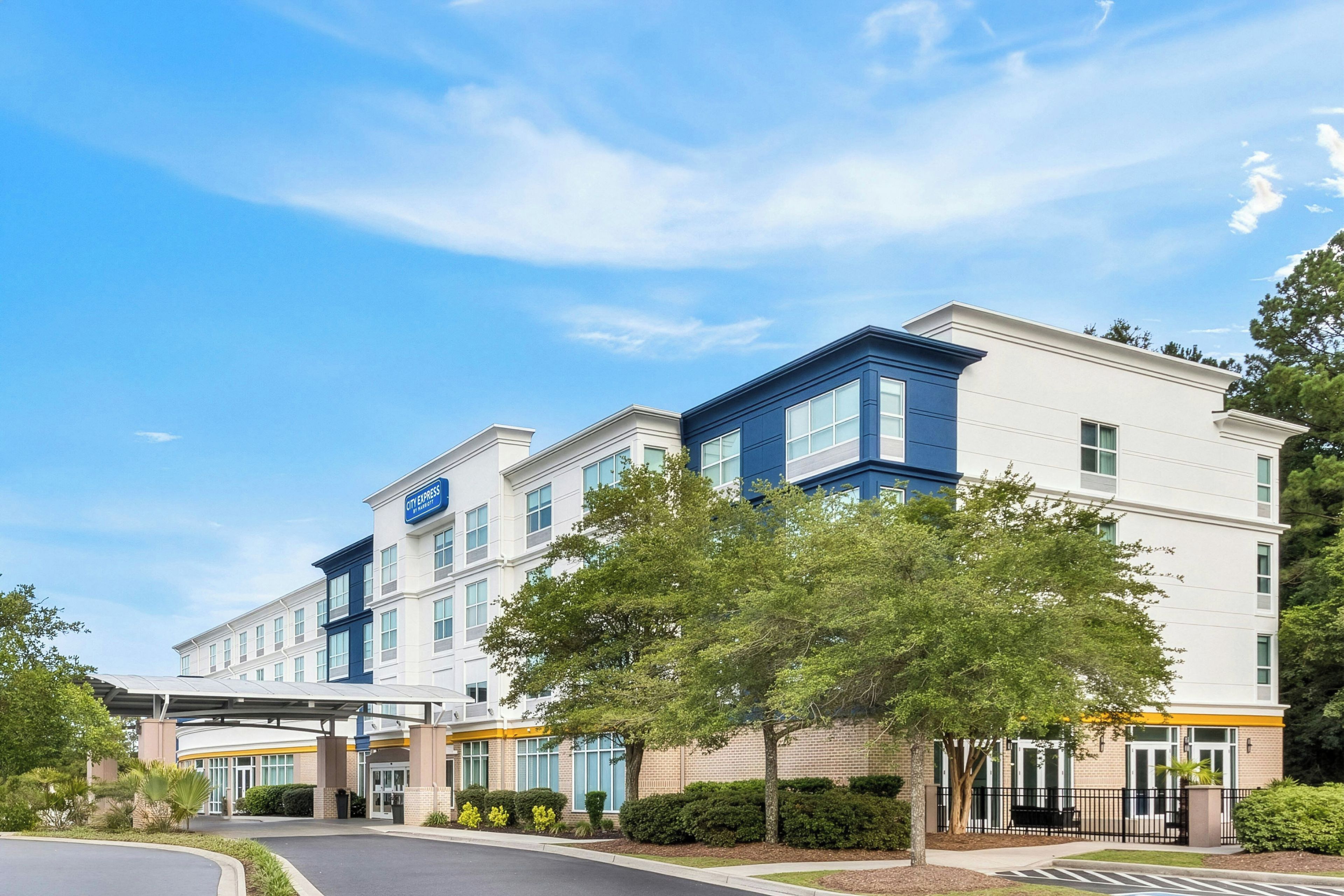 A hotel with a covered entrance, multiple floors, and a clear sky.